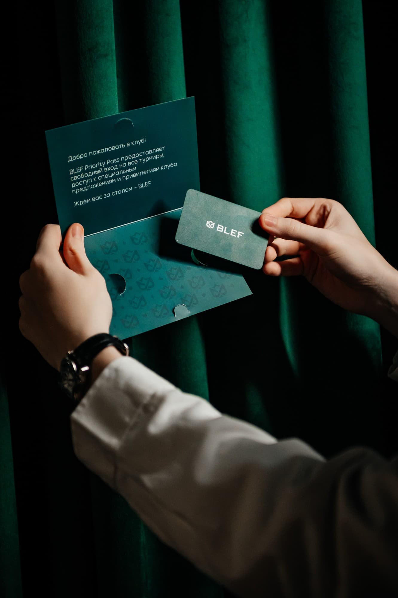 Клубная карта BLEF Priority Pass в руках гостя на фоне зелёного бархата